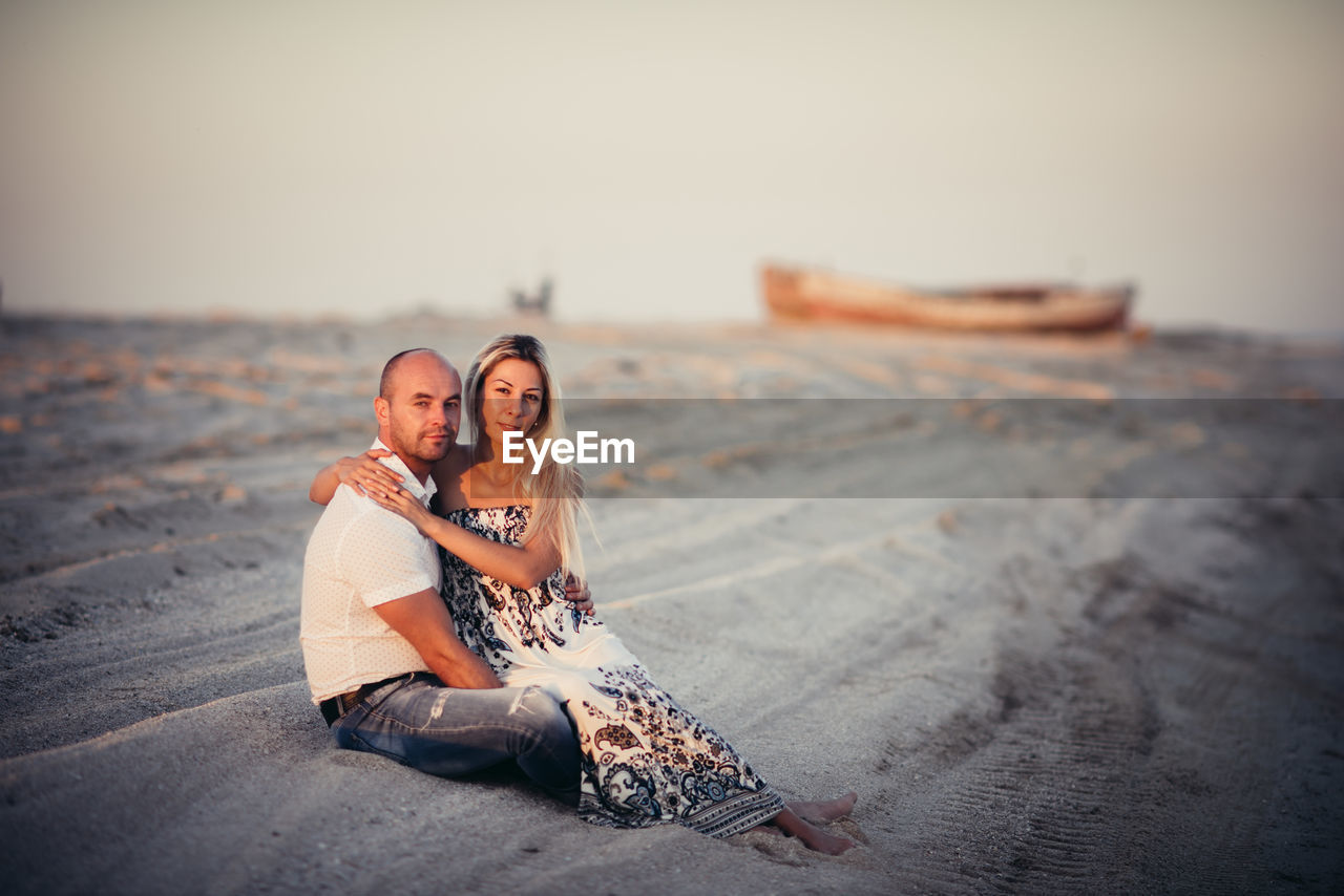 Happy young couple enjoying on a sandy beach at sunset.