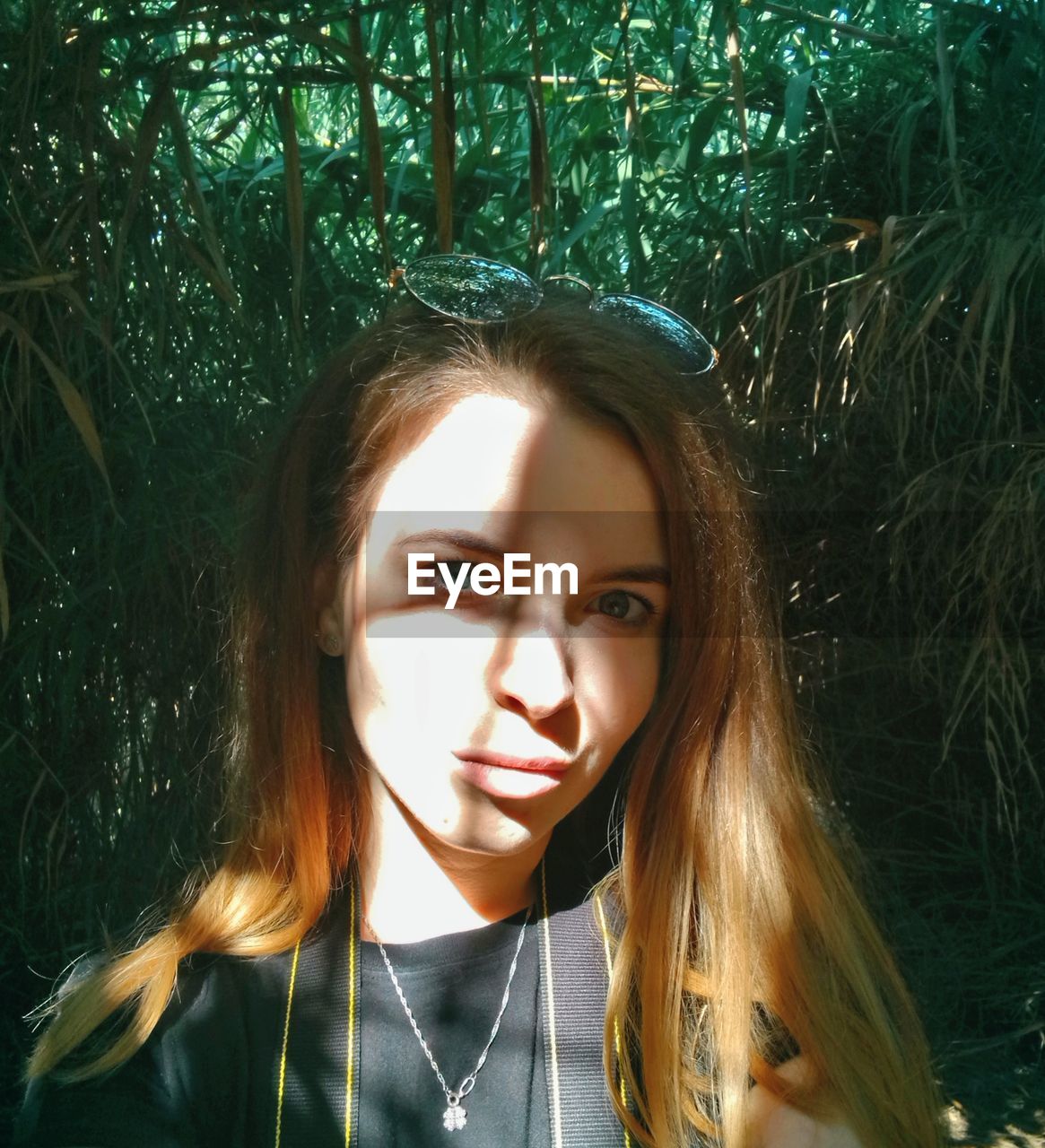 Portrait of beautiful young woman standing against plants in forest