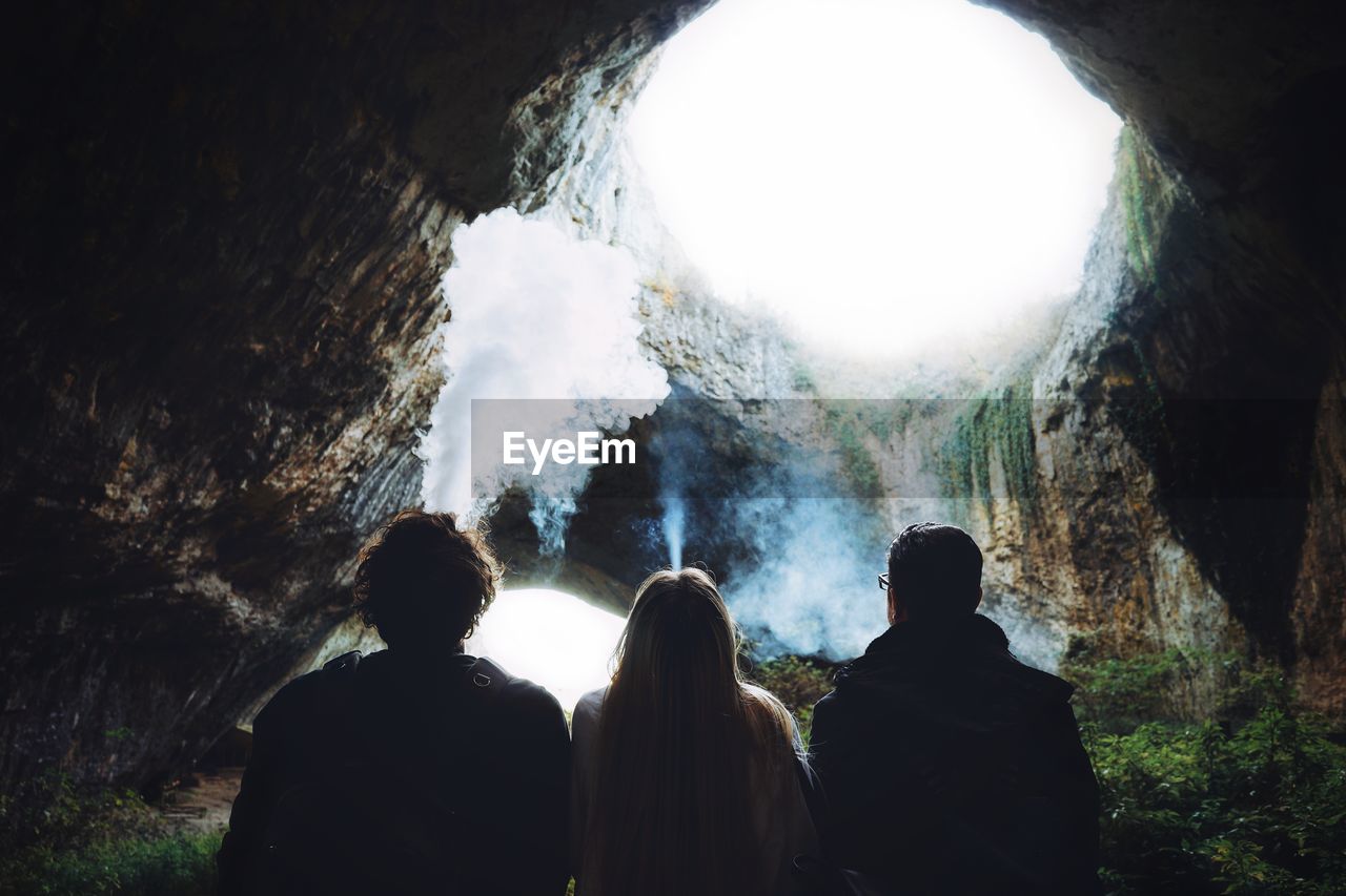 Rear view of people smoking in cave