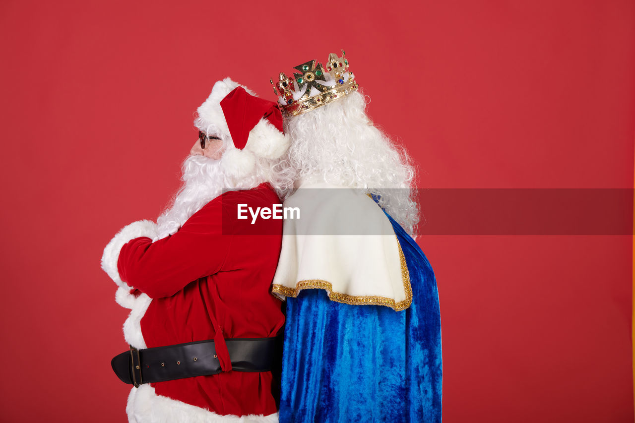 Papa noel vs rey mago on a red background
