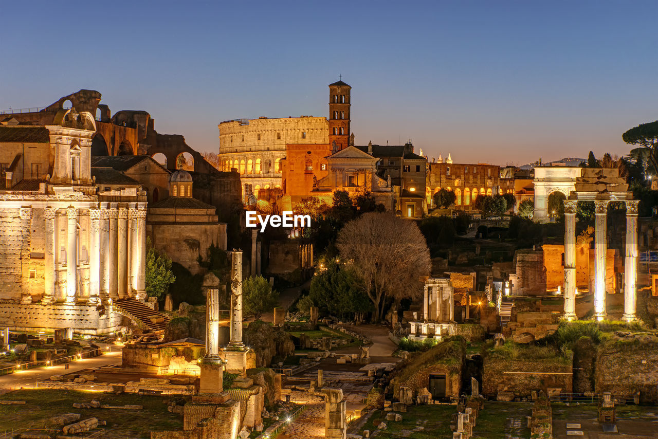 View over the ruins of the roman forum in rome at dawn with the colosseum in the back