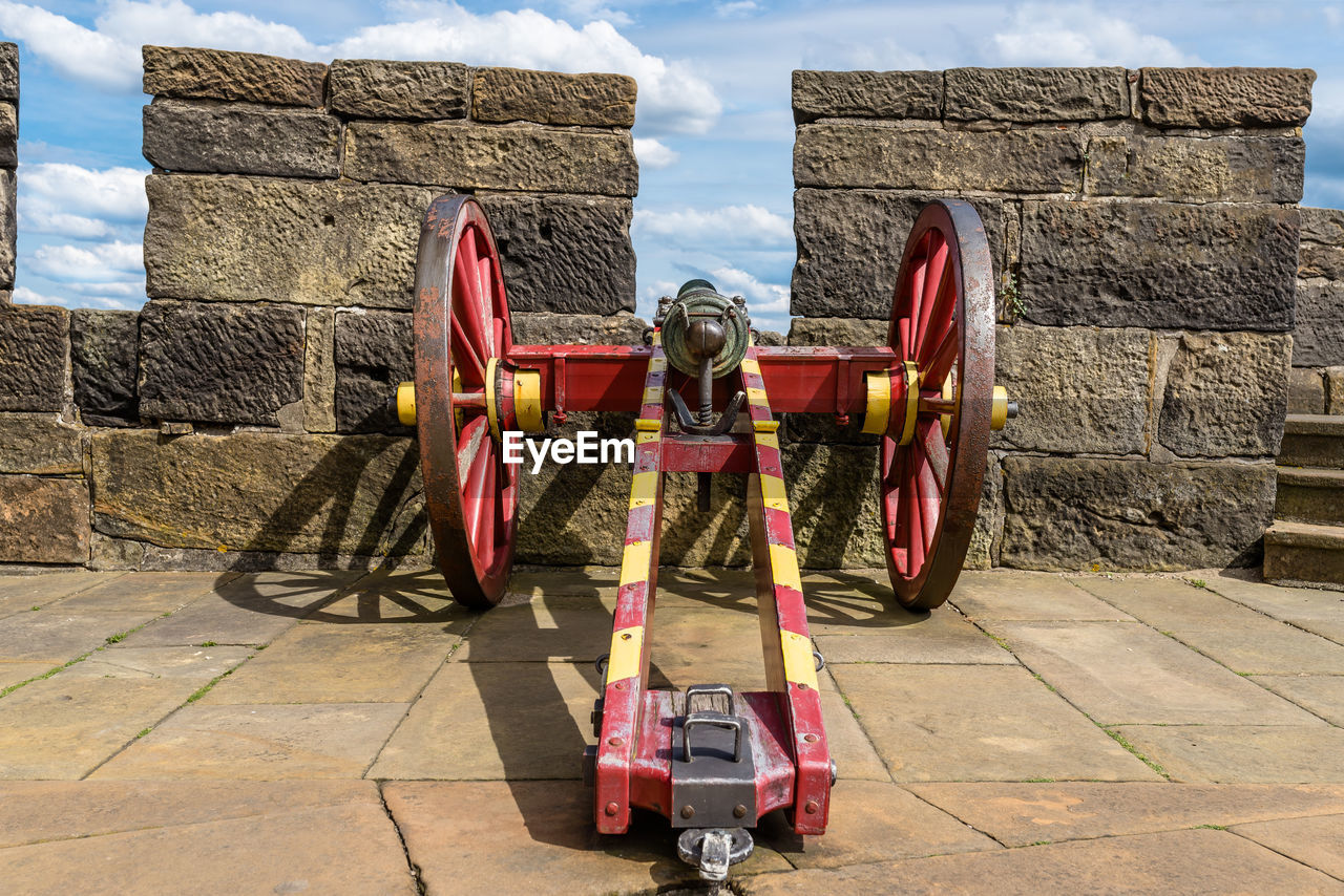 An antique cannon in red-yellow color on the walls of a medieval castle.