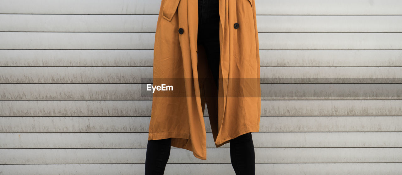 Midsection of woman standing against corrugated iron