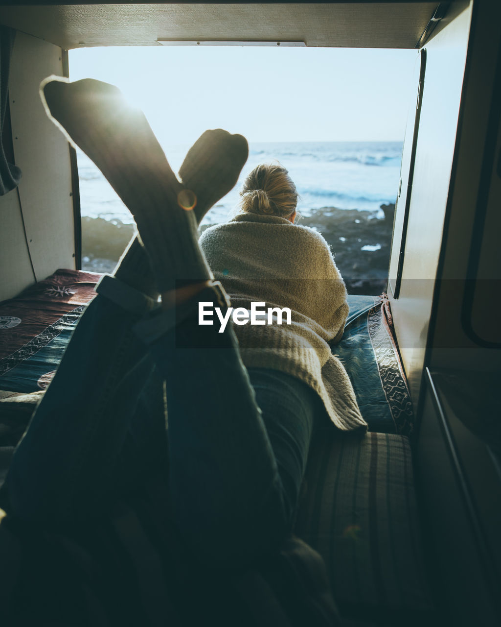 Rear view of woman lying by window at home