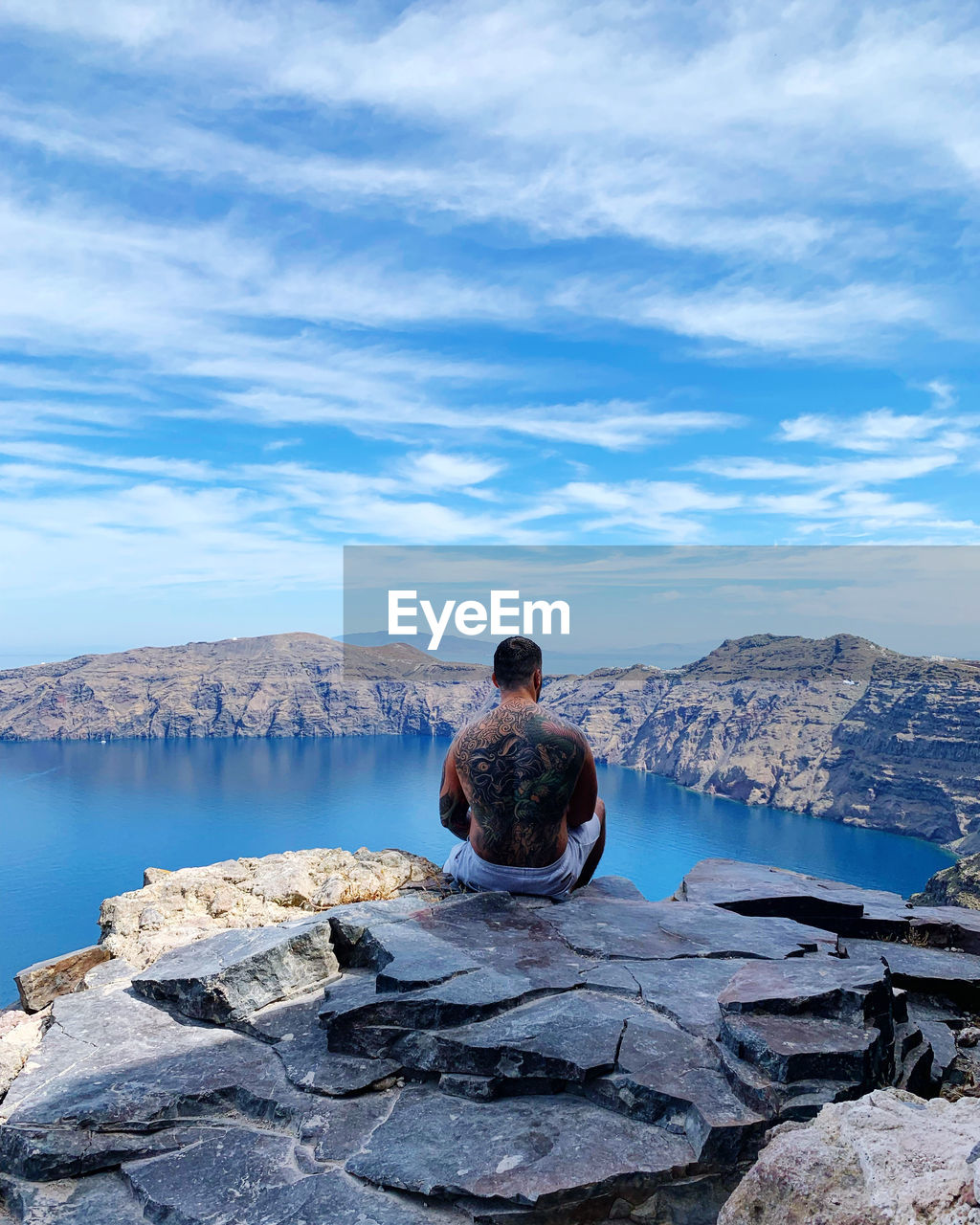 Rear view of shirtless man sitting on mountain