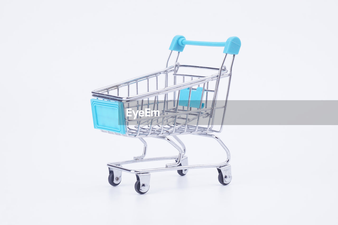 Close-up of miniature shopping cart against white background