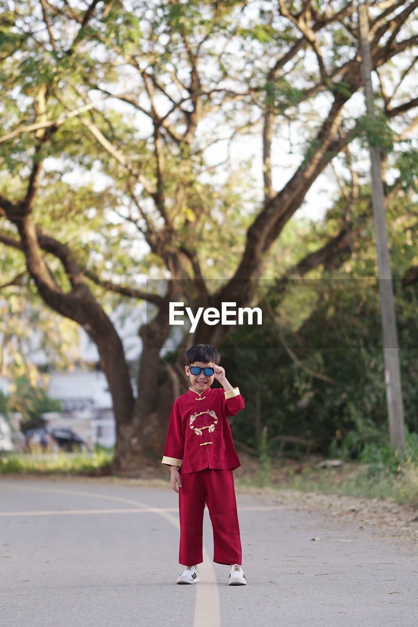 REAR VIEW OF BOY STANDING ON ROAD