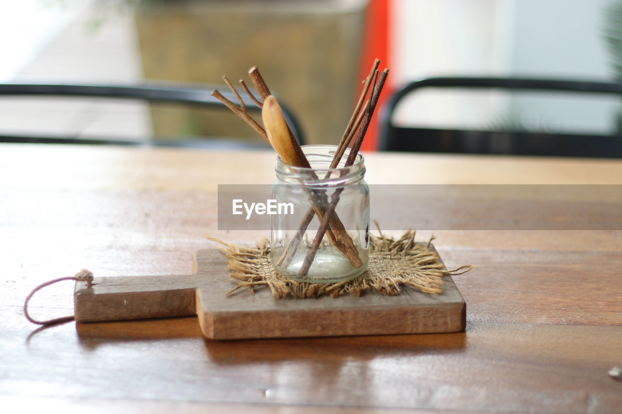 Close-up of sticks in glass jar on cutting board over table