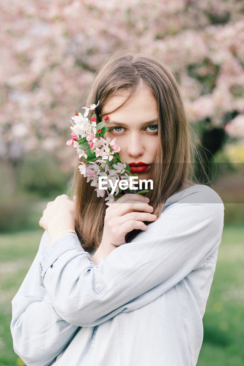 Portrait of a young woman holding spring flowers