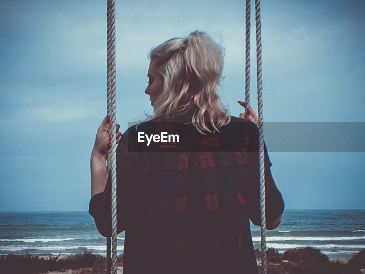 Rear view of woman on swing at beach