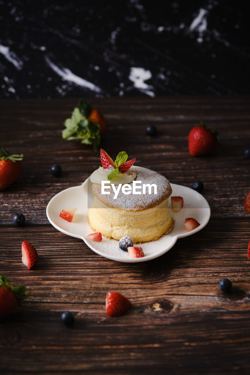CLOSE-UP OF CAKE ON TABLE AGAINST WOODEN WALL