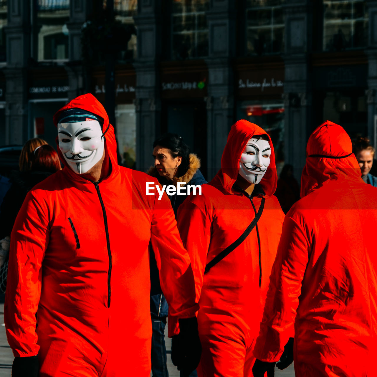 GROUP OF PEOPLE STANDING IN FRONT OF RED BUILDING