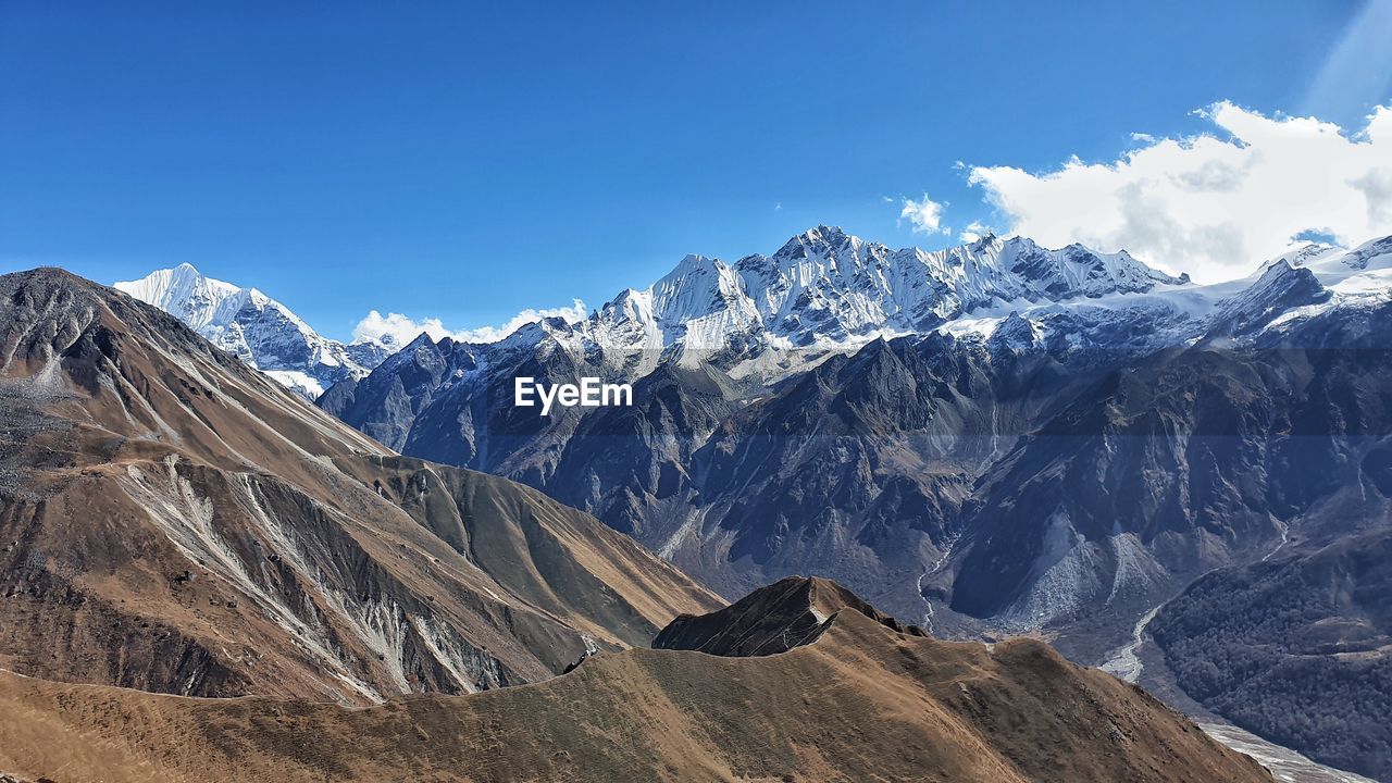 Scenic view of snowcapped mountains against blue sky