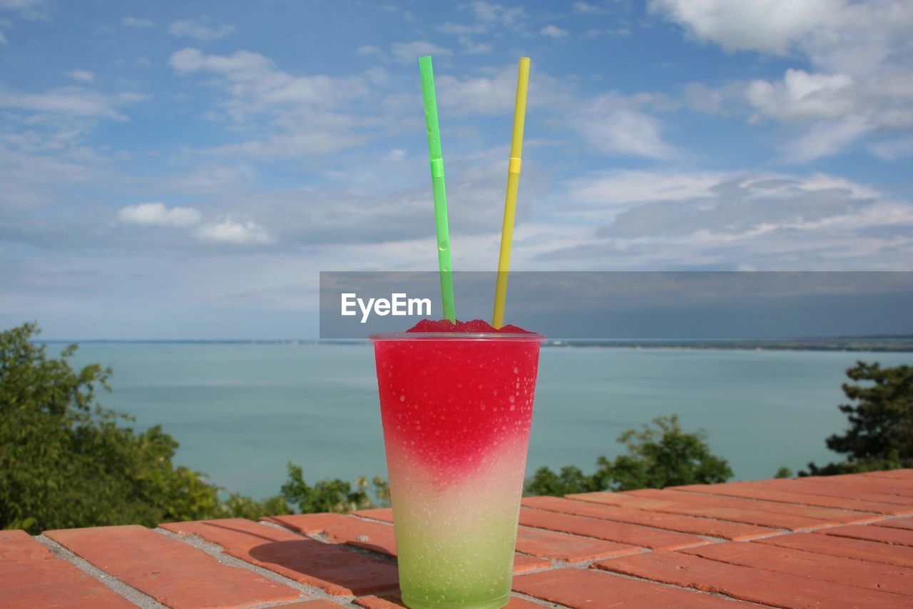 CLOSE-UP OF DRINK AGAINST SEA