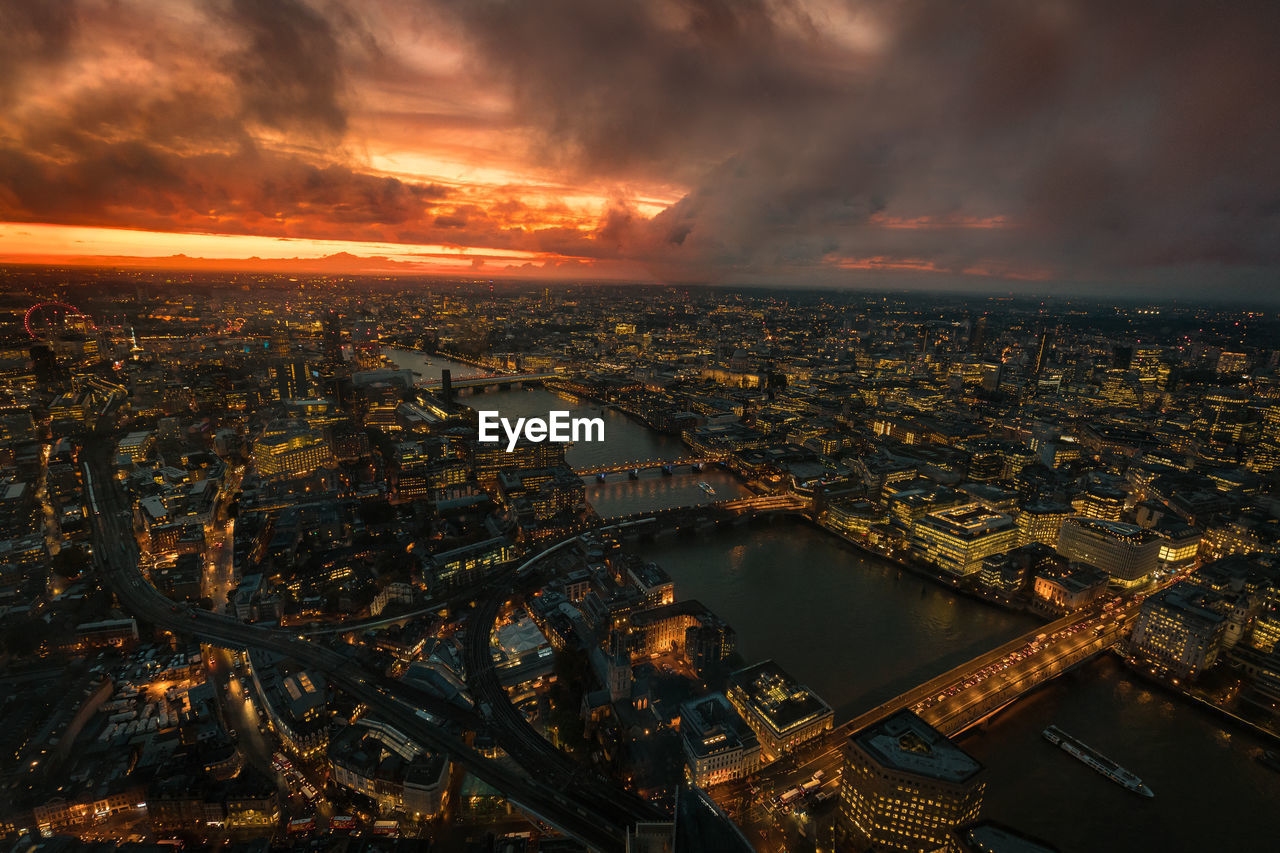 Aerial view of illuminated cityscape against sky during sunset