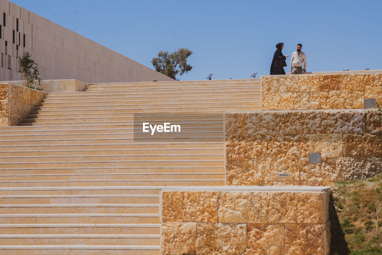 LOW ANGLE VIEW OF PEOPLE ON WALL