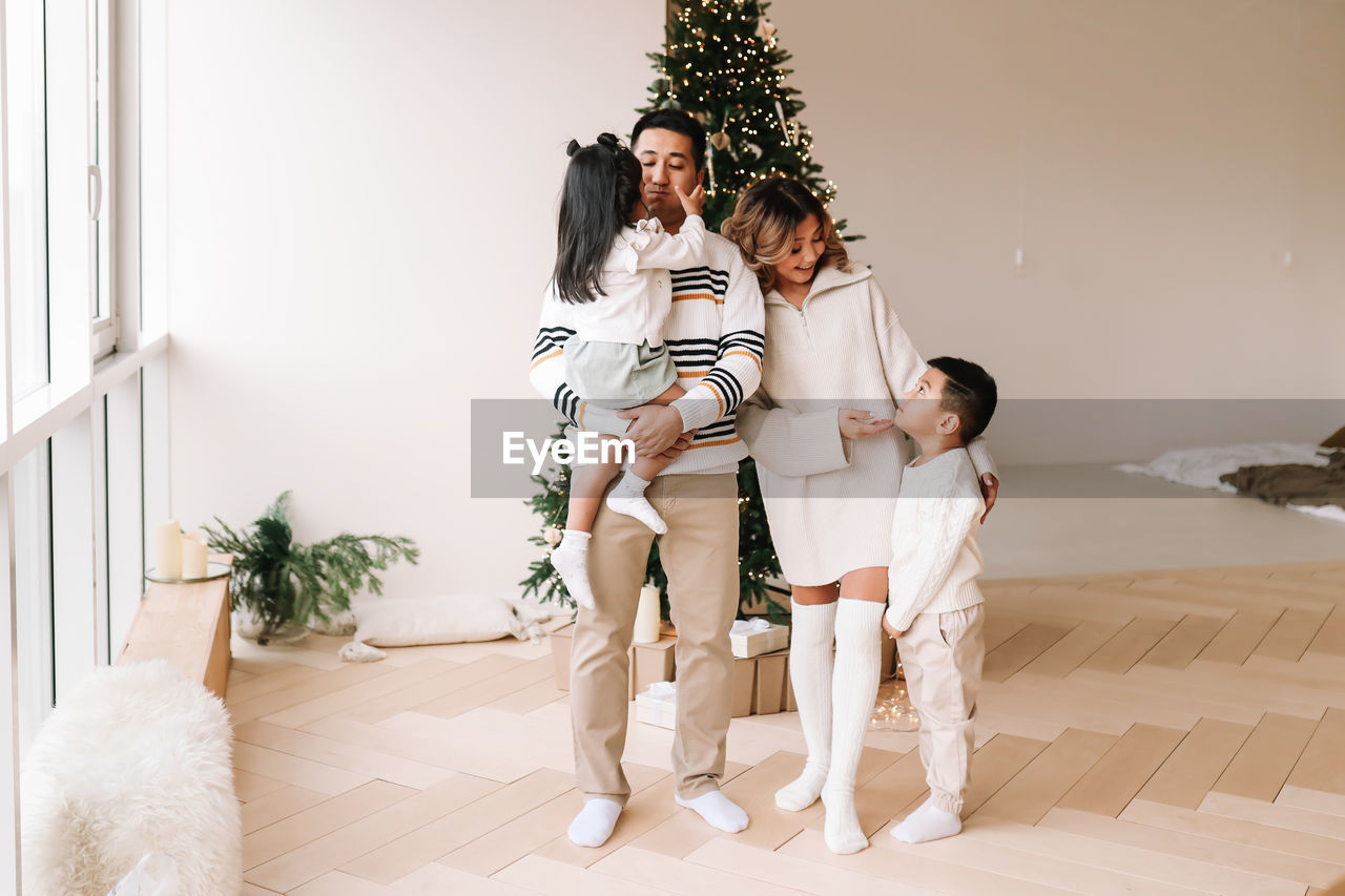 An asian multi-racial family with two children celebrate the christmas holiday in a decorated indoor