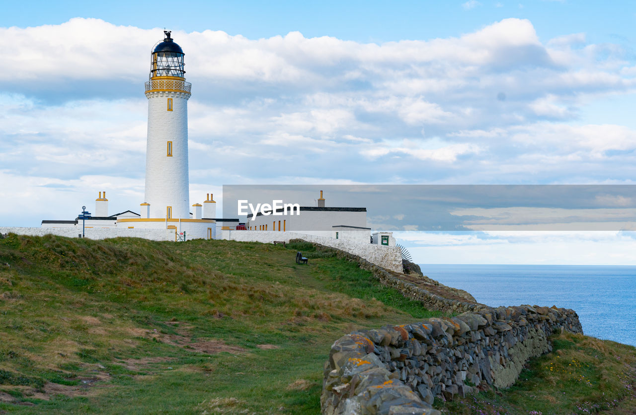 Lighthouse by sea against sky