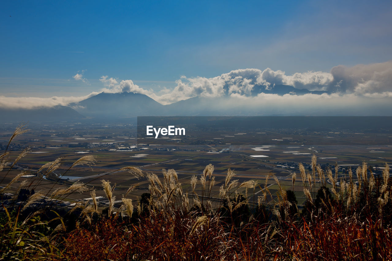 Scenic view of farm fields against sky with volcanic mountains in background