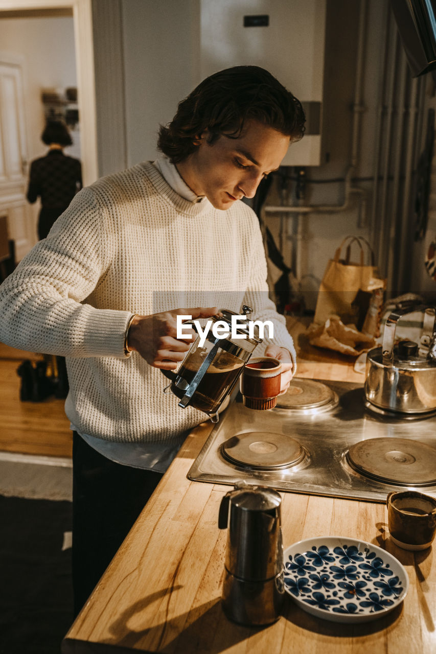 Man pouring coffee in cup at home