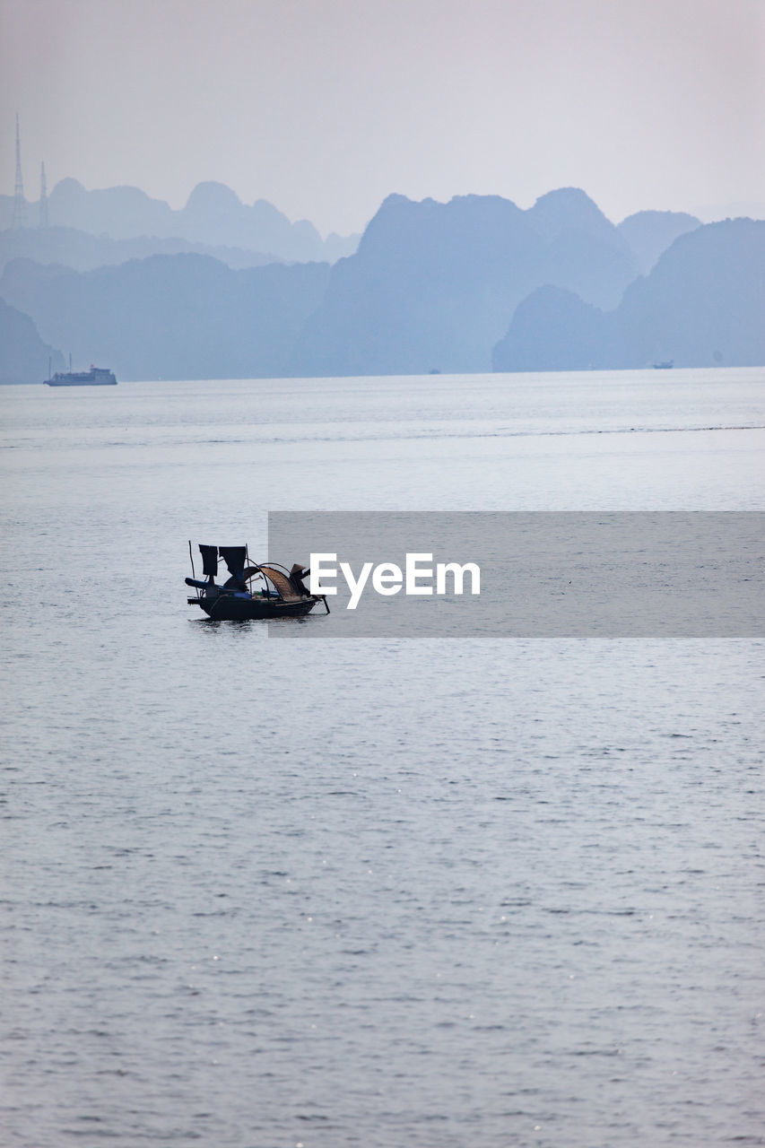 Boat sailing on sea against mountains