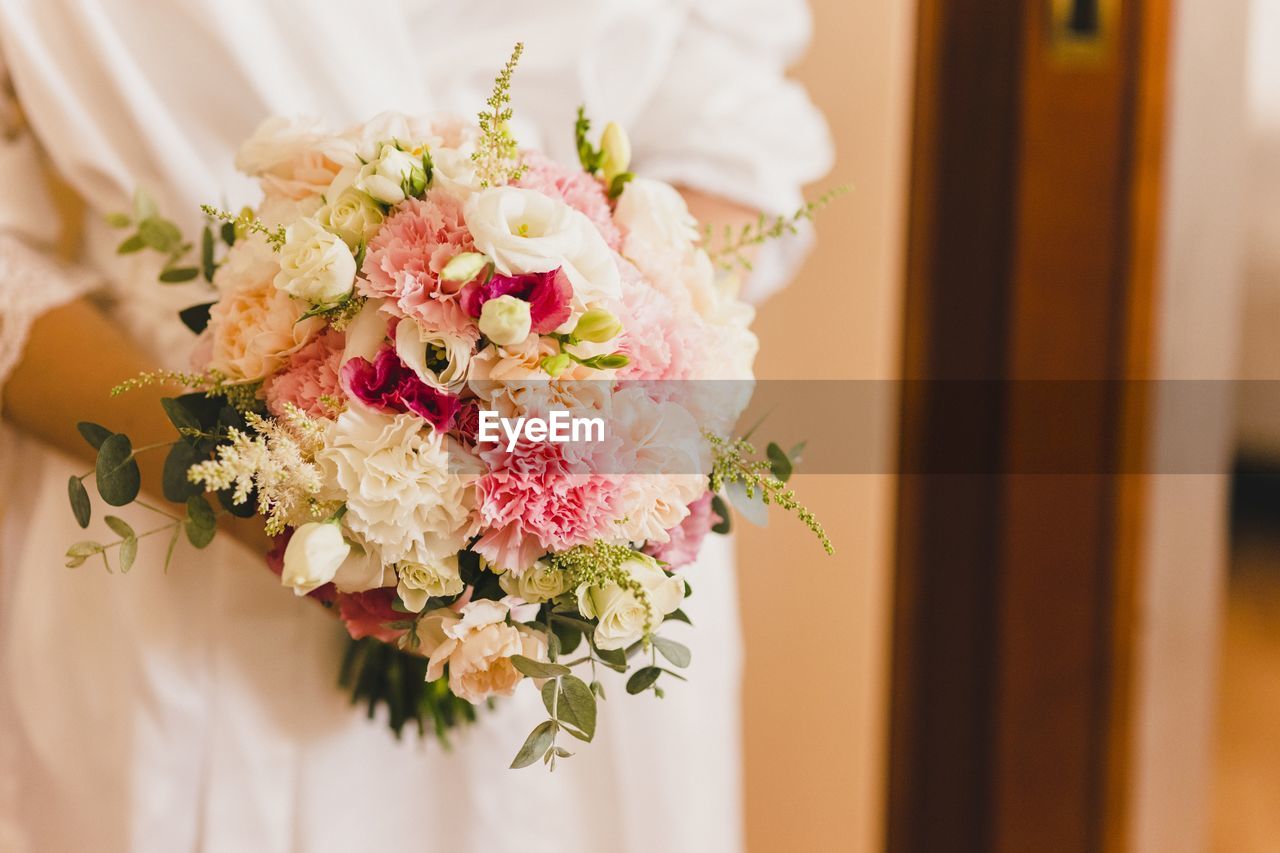 Midsection of bride holding bouquet