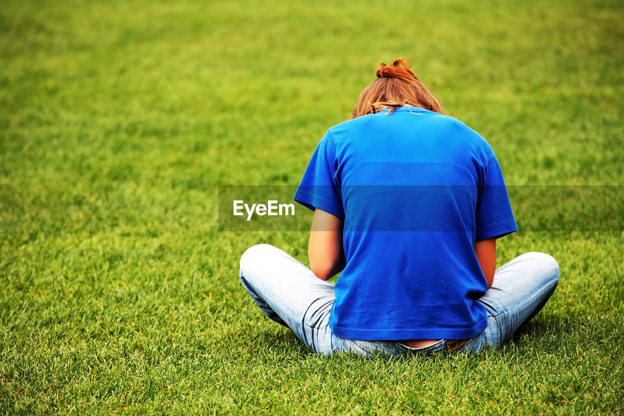 Rear view of woman sitting on grassy field