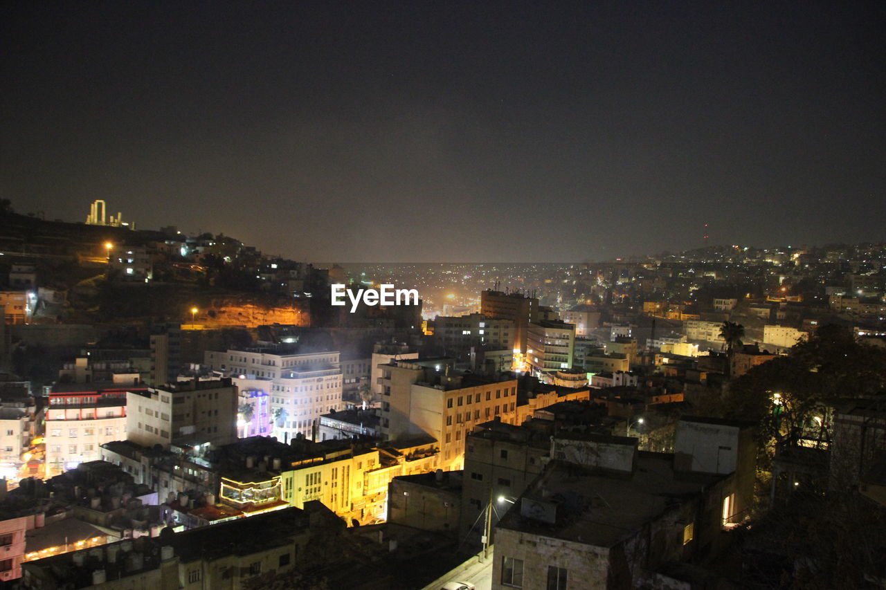 HIGH ANGLE VIEW OF ILLUMINATED BUILDINGS IN CITY AGAINST SKY