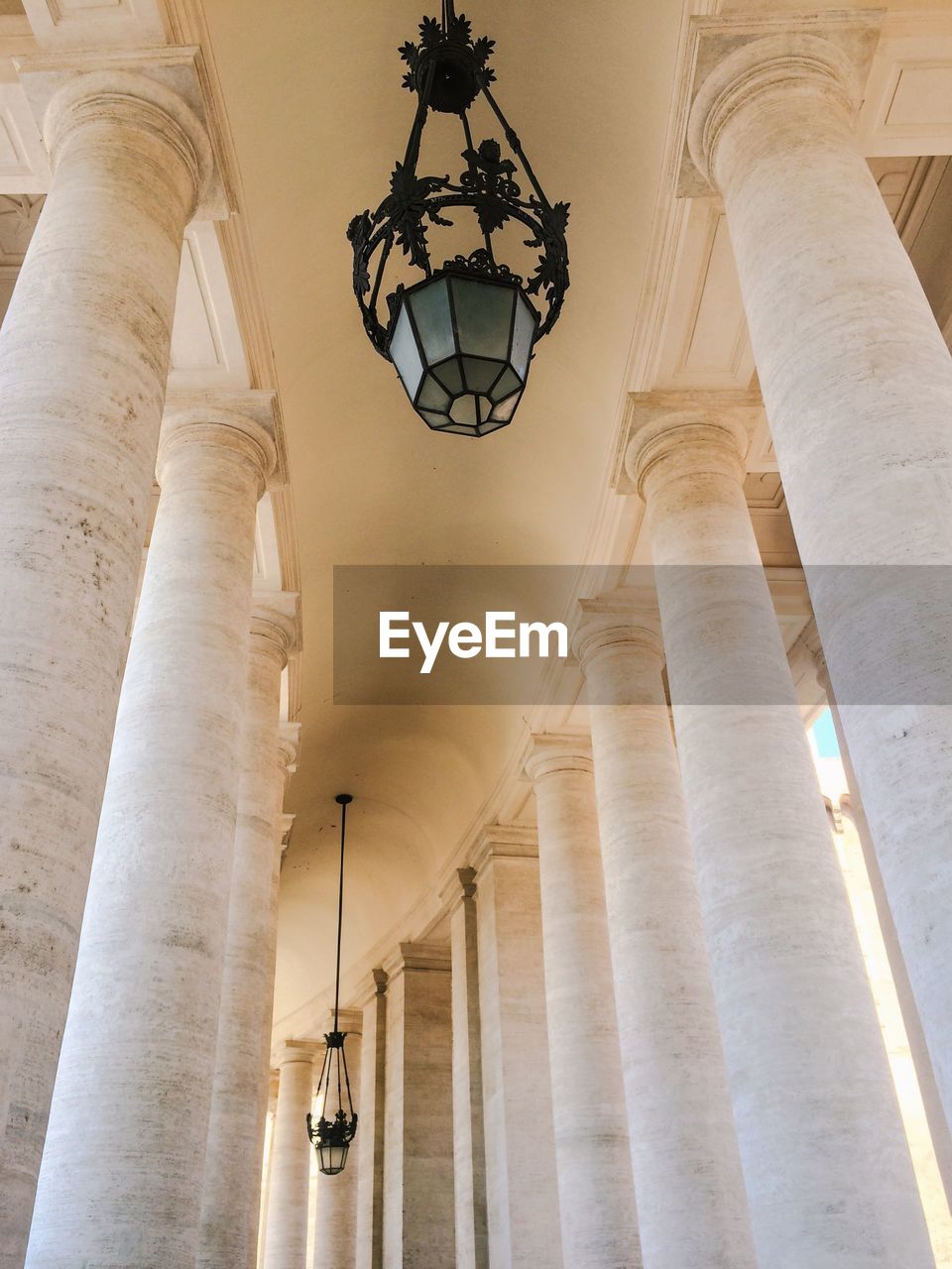 Low angle view of lighting equipment hanging from ceiling in historic building