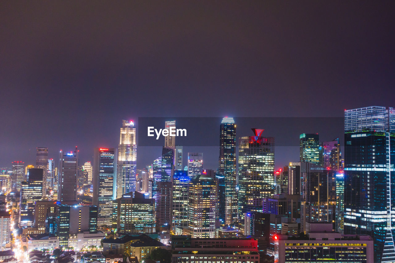 Illuminated buildings in city against sky at night