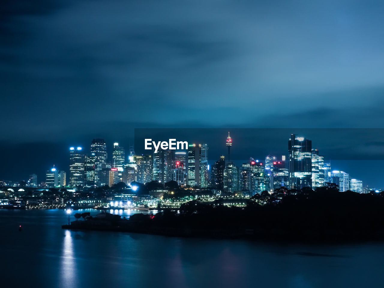 ILLUMINATED CITYSCAPE BY SEA AGAINST SKY