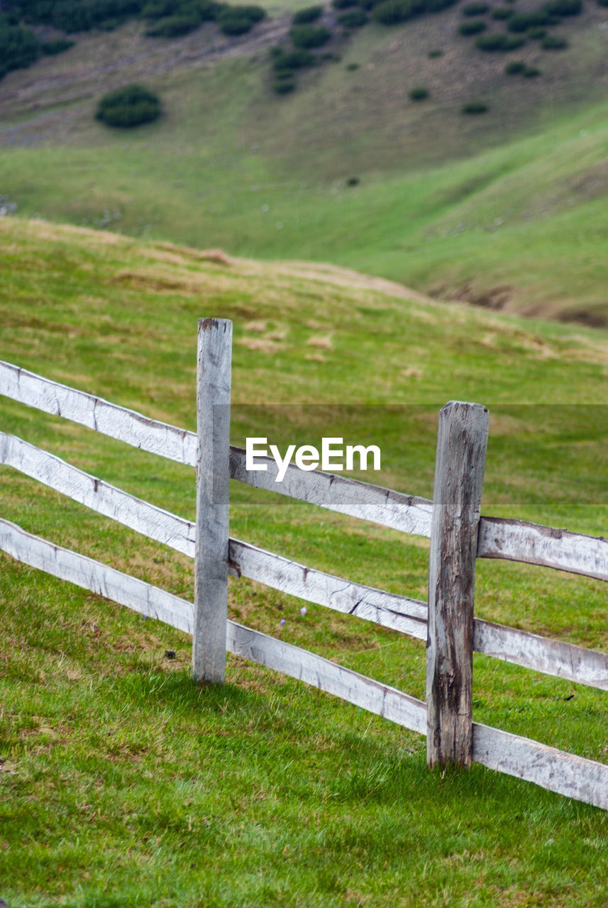 WOODEN FENCE ON FIELD BY FARM