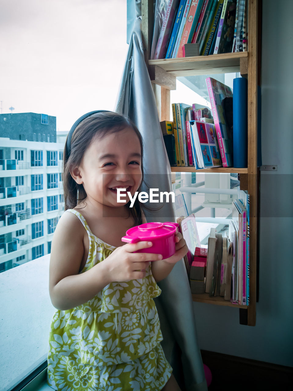 Toddler girl playing toy kitchen at home.