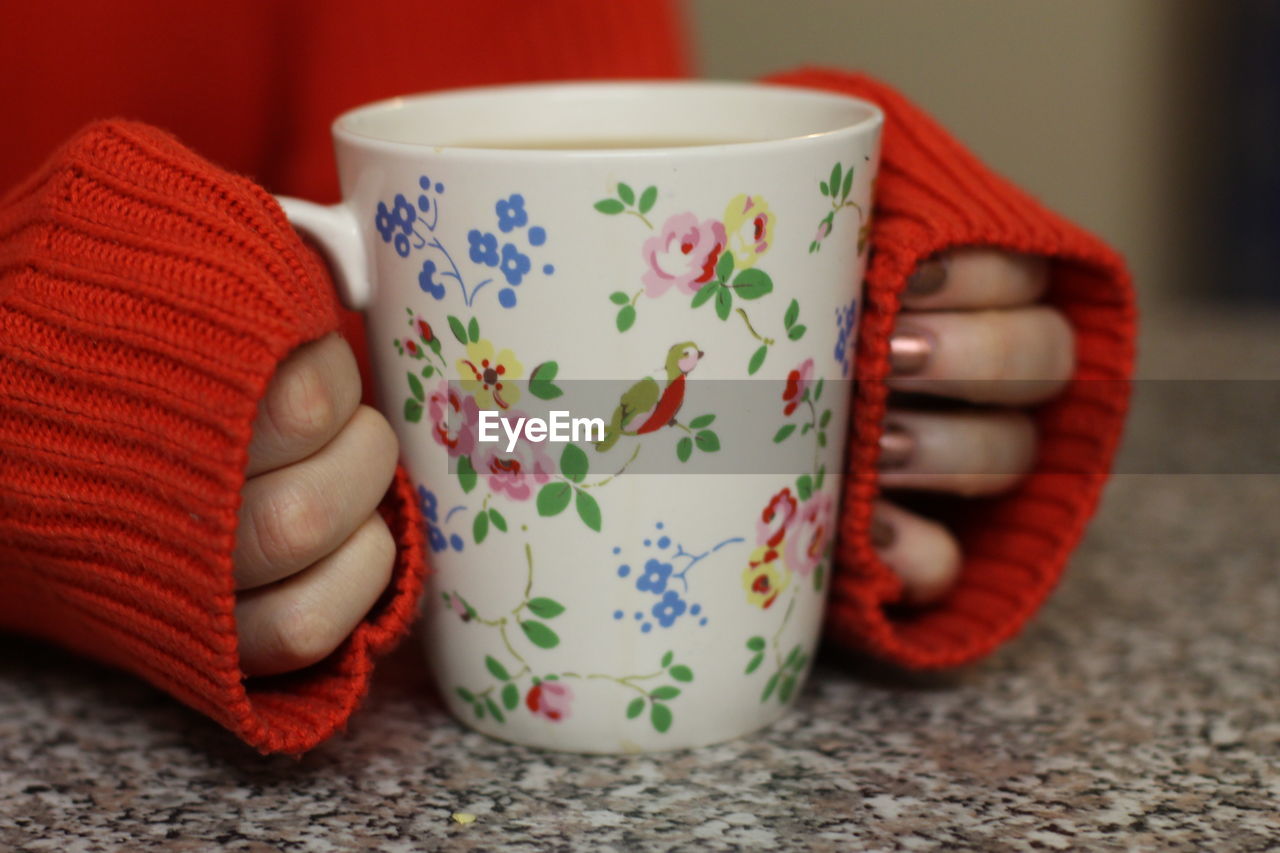 Close-up of hand holding tea cup on table