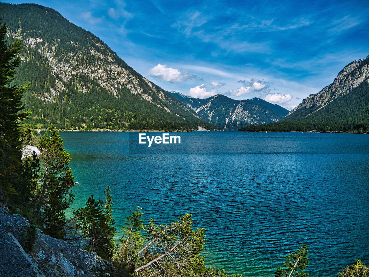 Scenic view of lake by mountains against blue sky