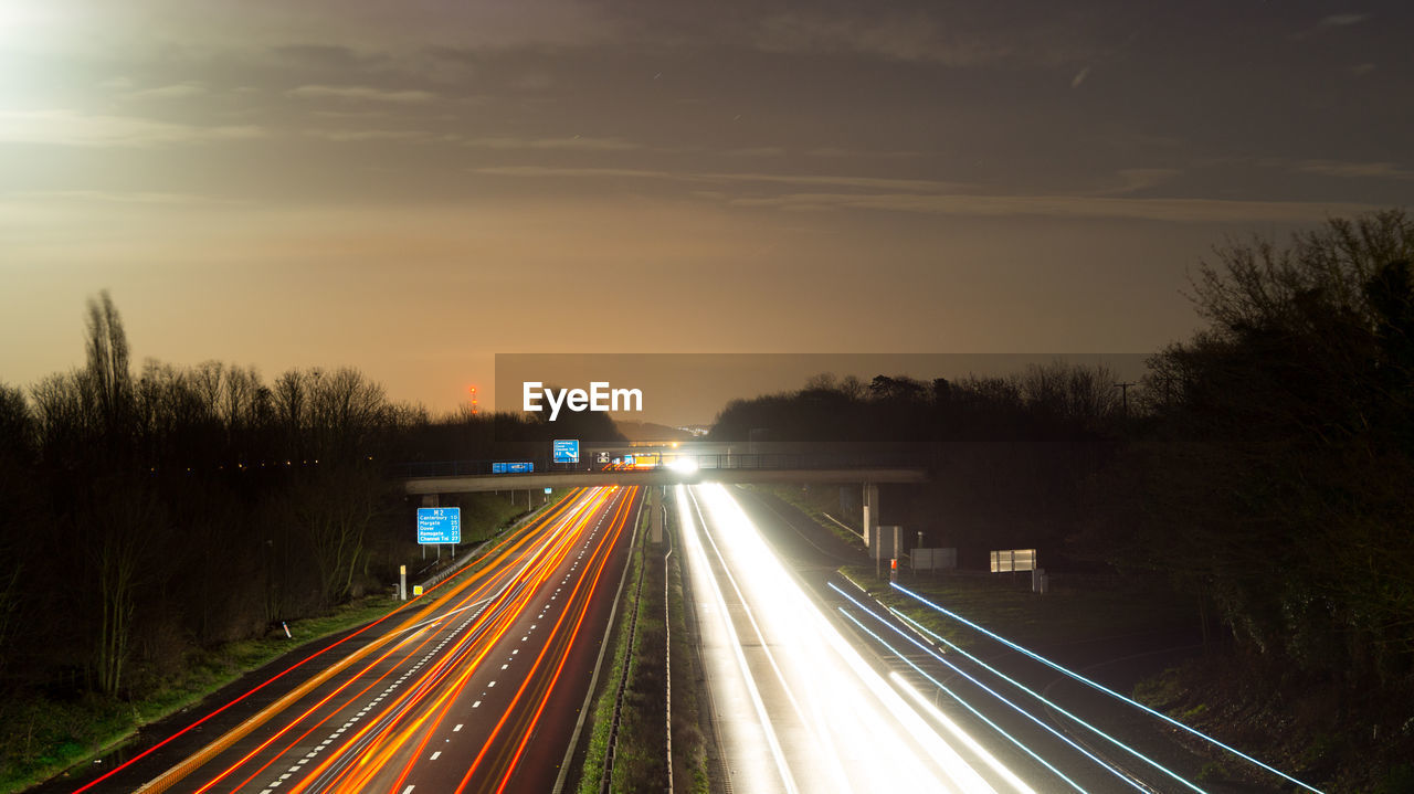 Light trails on road against sky