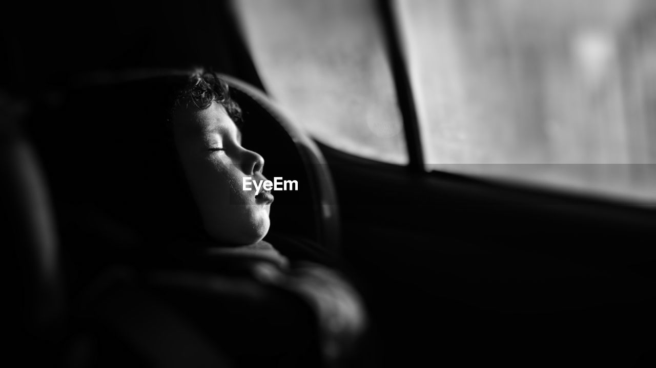 Close-up portrait of little boy sleeping in car