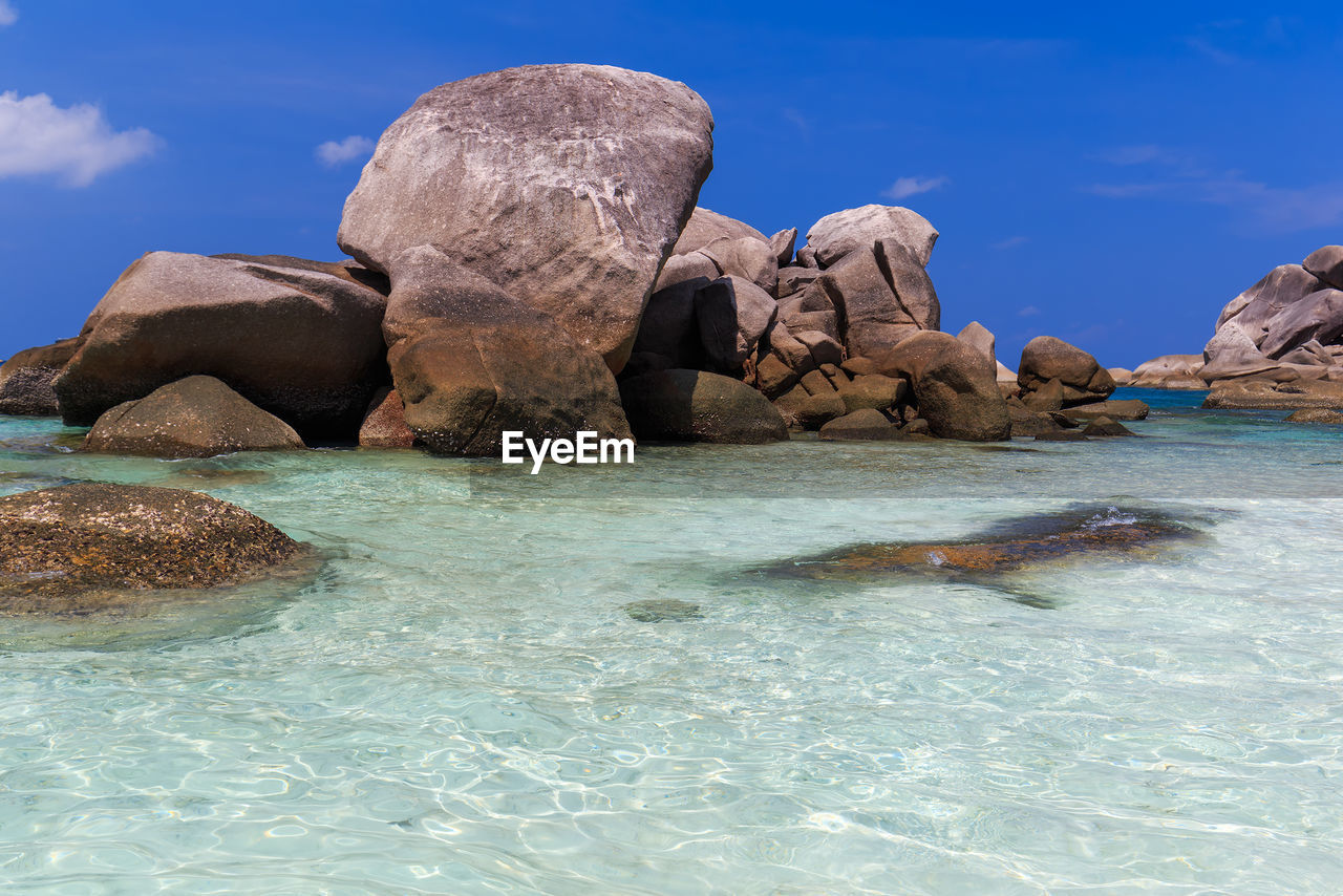 VIEW OF ROCK FORMATION IN SEA AGAINST BLUE SKY