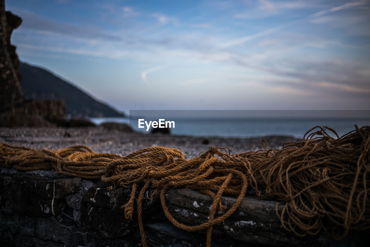 Close-up of fishing net on beach against sky