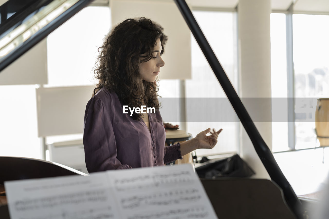 Businesswoman standing by piano in office