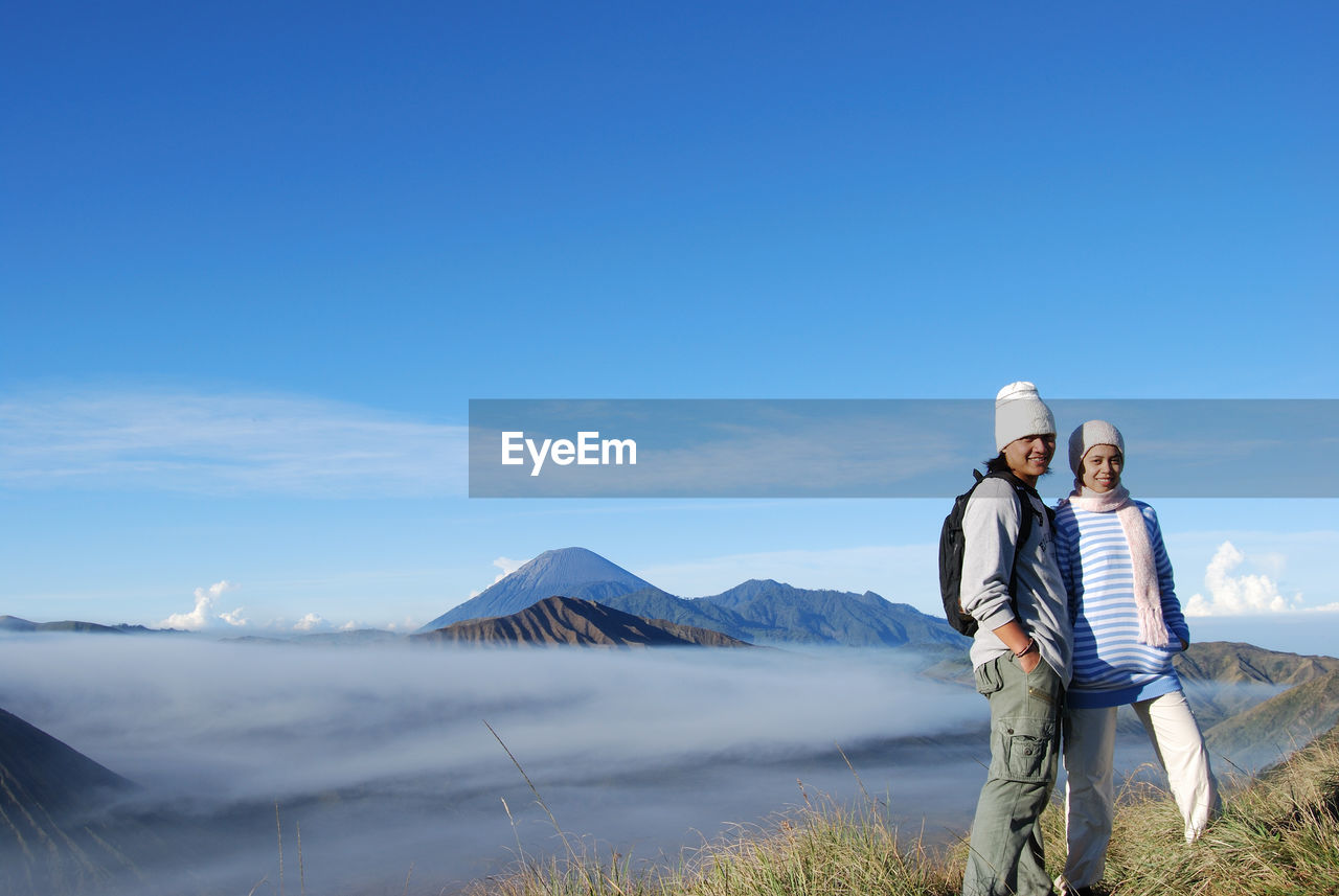 Couple on mountain against blue sky