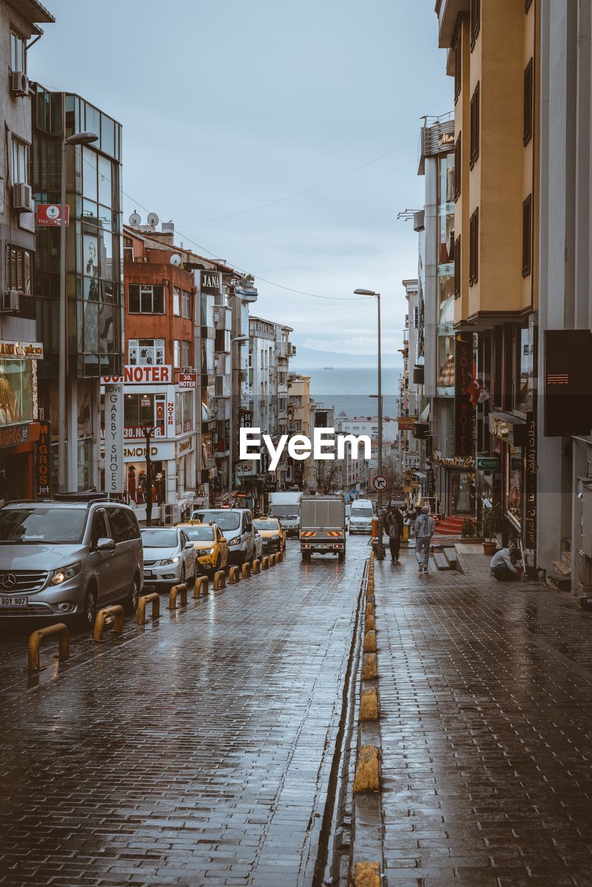Wet street amidst buildings in city during rainy season