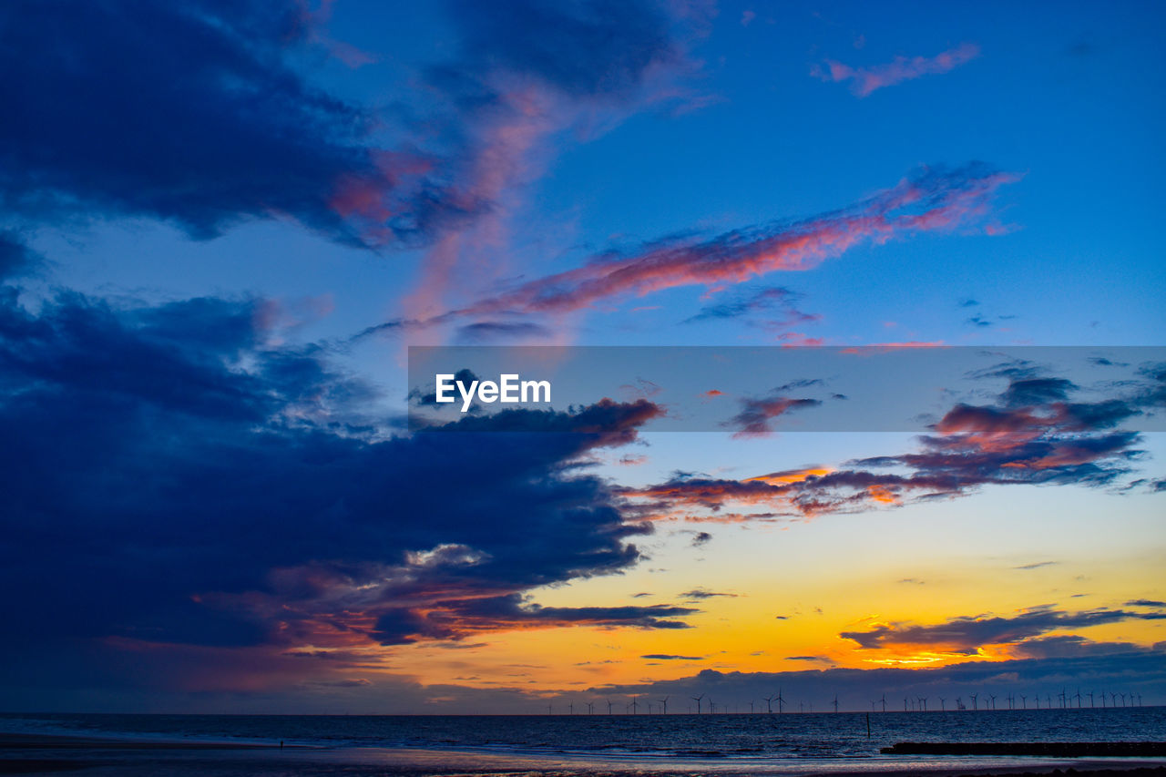 Scenic view of sea against dramatic sky during sunset