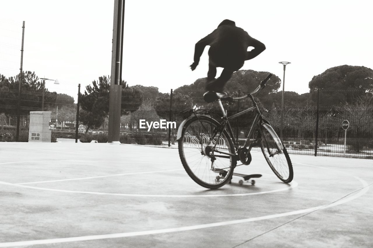 Man performing stunt on bicycle at city square against clear sky