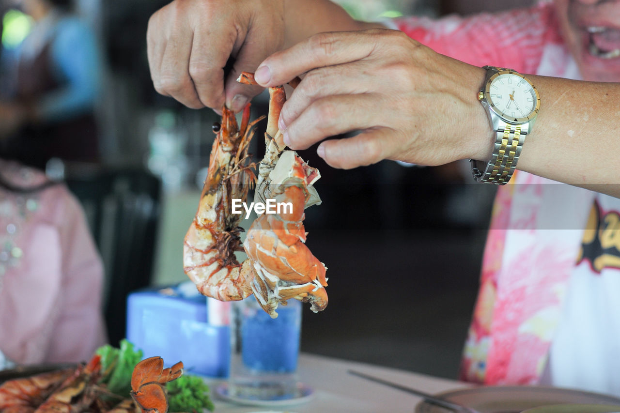 Closeup hands of man holding the steamed shrimp and clap.