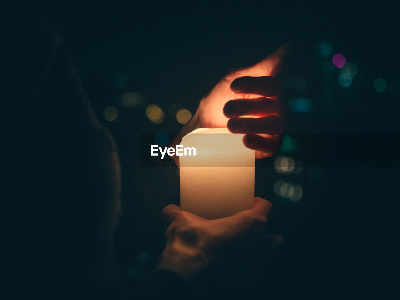 Close-up of hand holding illuminated candle