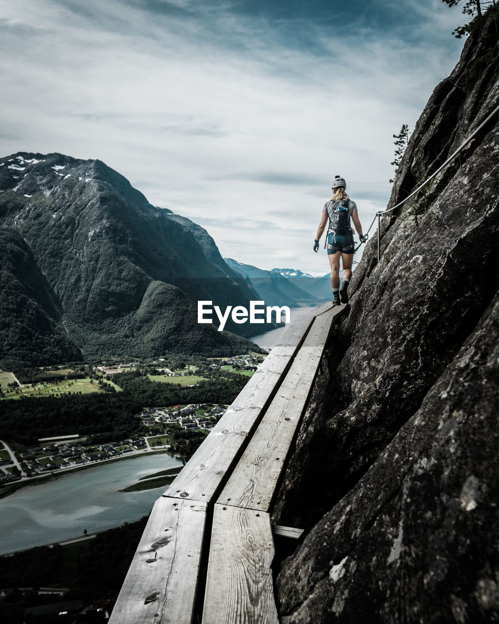 Rear view of woman walking on wood by mountain against sky