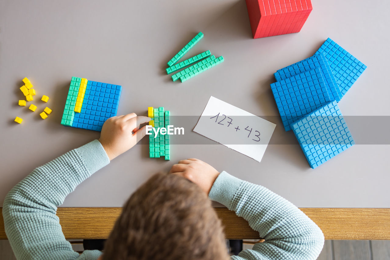 Little boy using the base 10 method to do addition at home