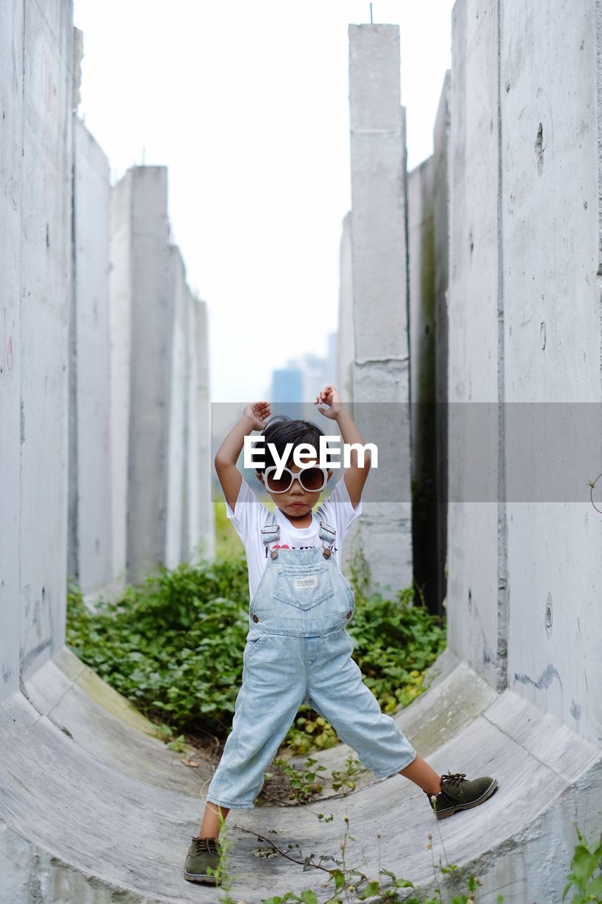 Cute girl wearing sunglasses while standing amidst built structure
