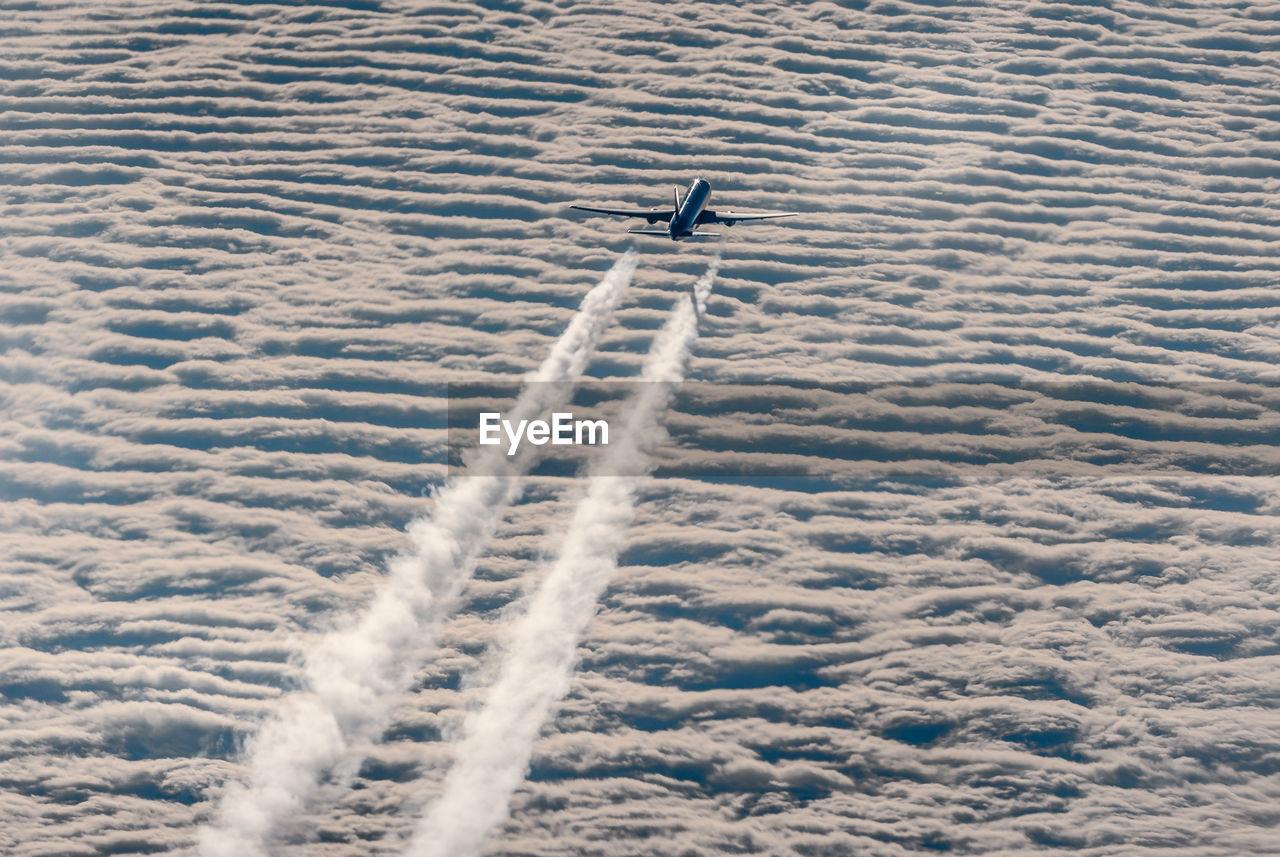Aerial view of airplane above closed layer of clouds